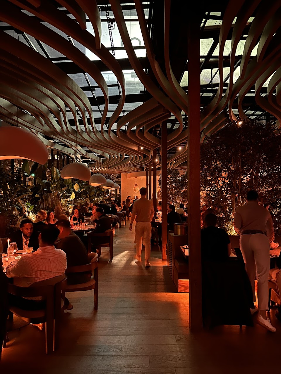 Warm dining room with sculptural ceiling and candlelit tables
