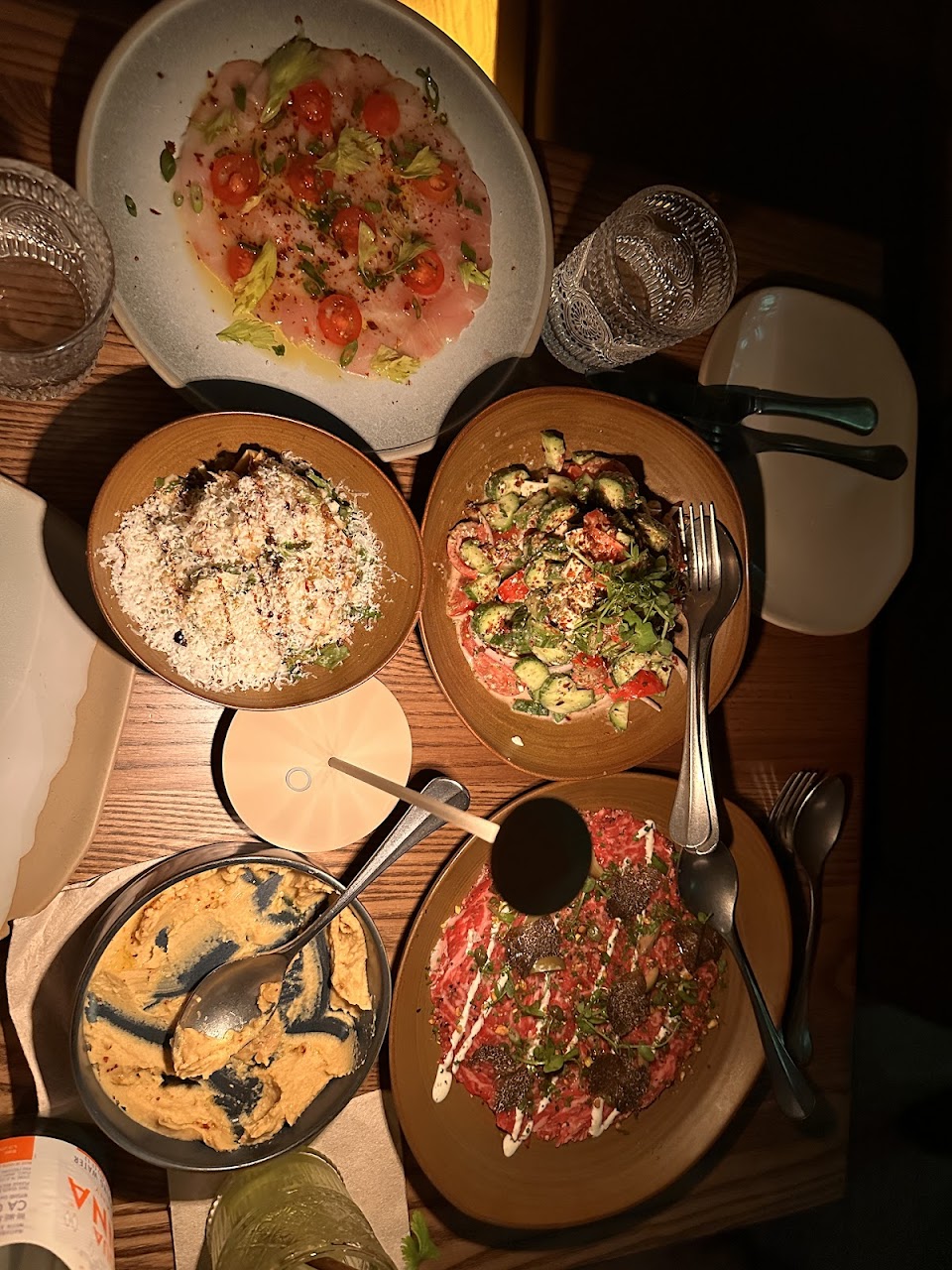 Shared Mediterranean table with dips, crudo, and salad