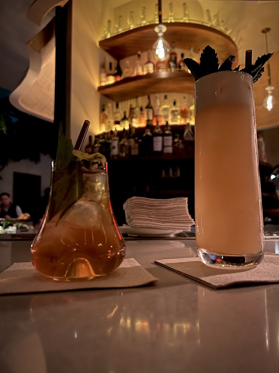 Two cocktails set against a softly lit bar